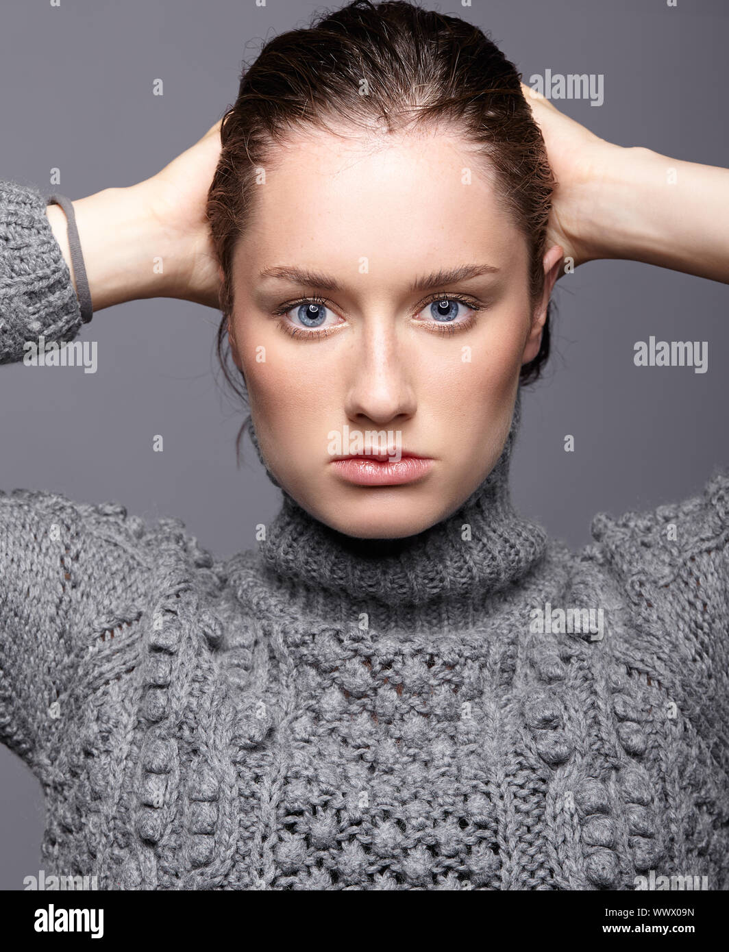 Portrait de beauté de jeune femme en laine gris. Fille brune avec des yeux bleus et maquillage femme jour Banque D'Images