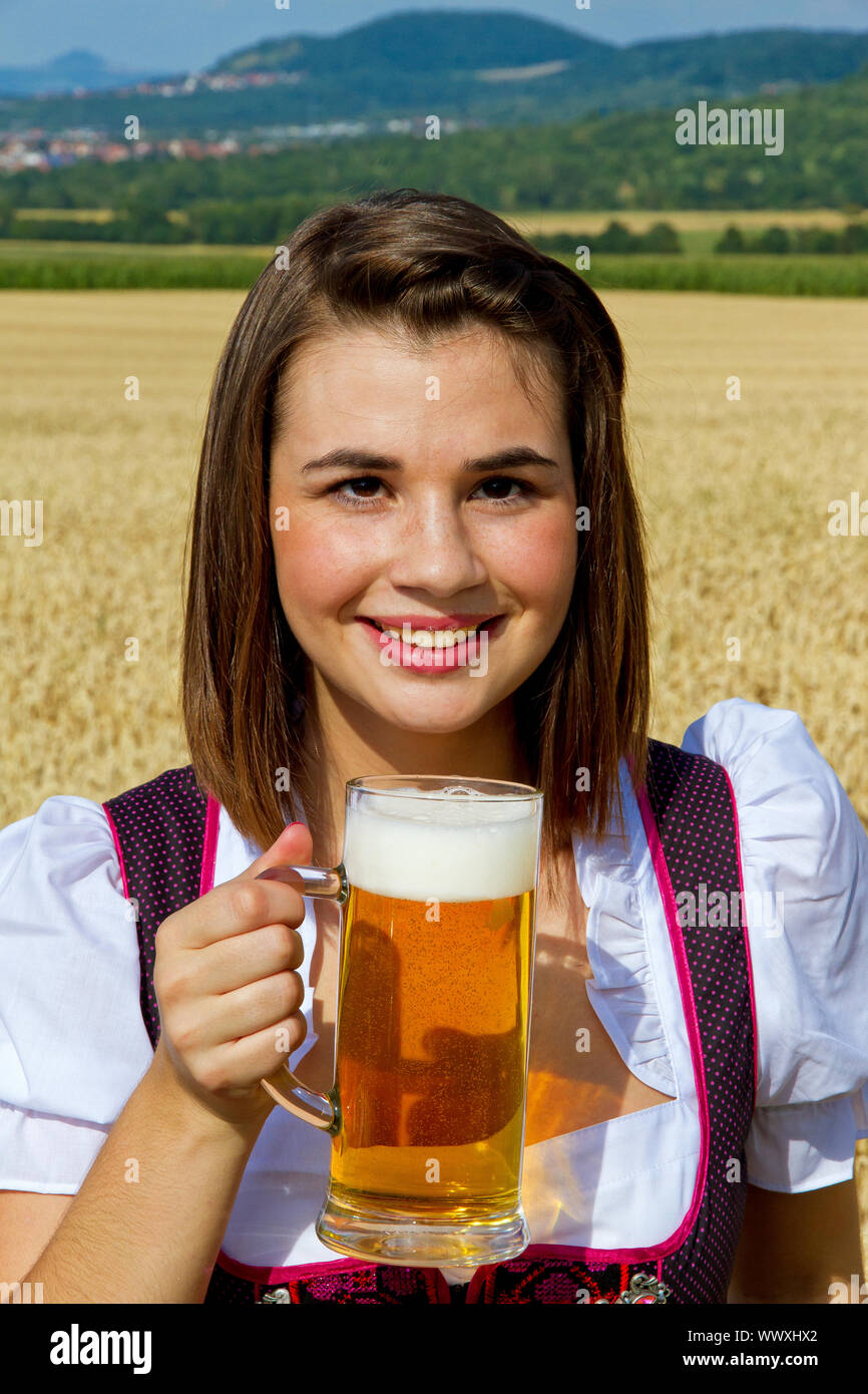 Jeune fille dans un Dirndl traditionnel de boire une bière et manger un bretzel dans la nature Banque D'Images