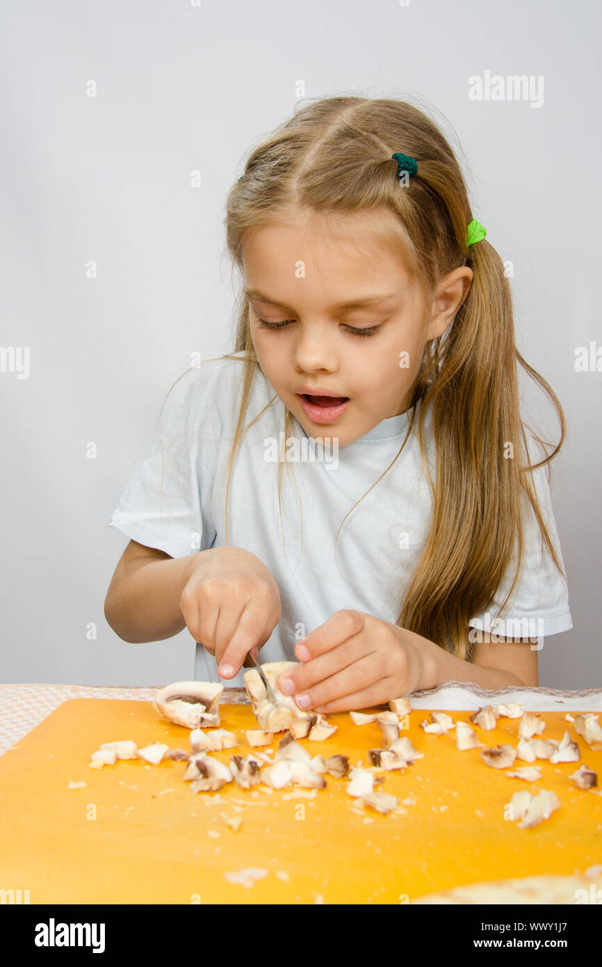La petite fille à la table avec diligence les champignons couteau Banque D'Images
