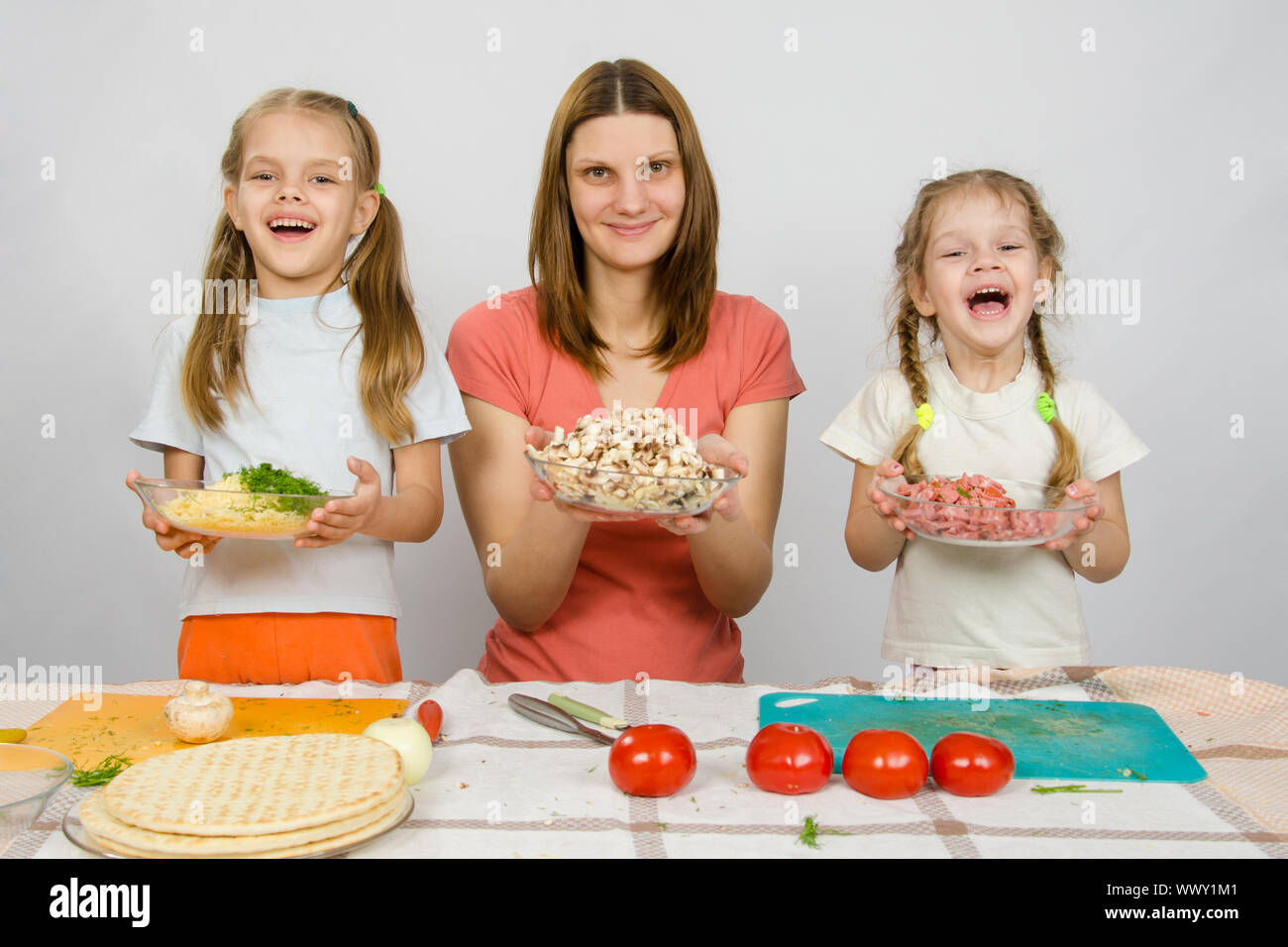 Mère de deux filles heureusement holding a plate avec des tranches de pizza pour produits Banque D'Images