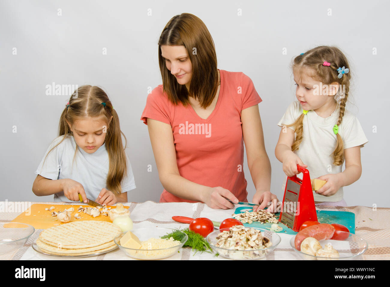 Maman d'une fille de cinq ans, vu que la fille aînée de champignons coupe pizza Banque D'Images