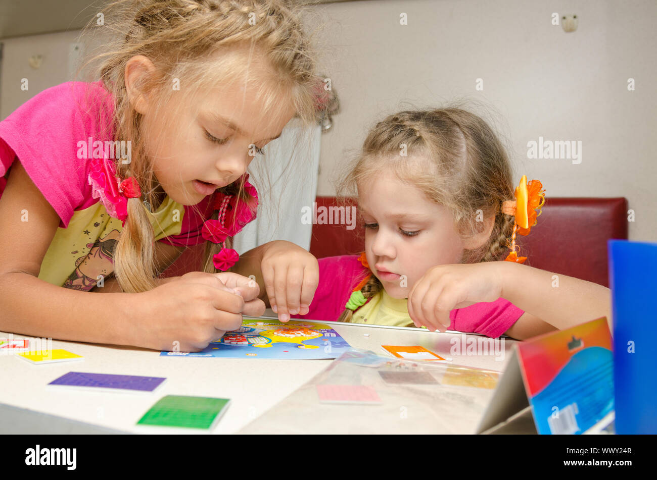 Deux filles sur le train assis à la table sur la partie inférieure de la classe de seconde place voiture et enthousiasme s'applique Banque D'Images