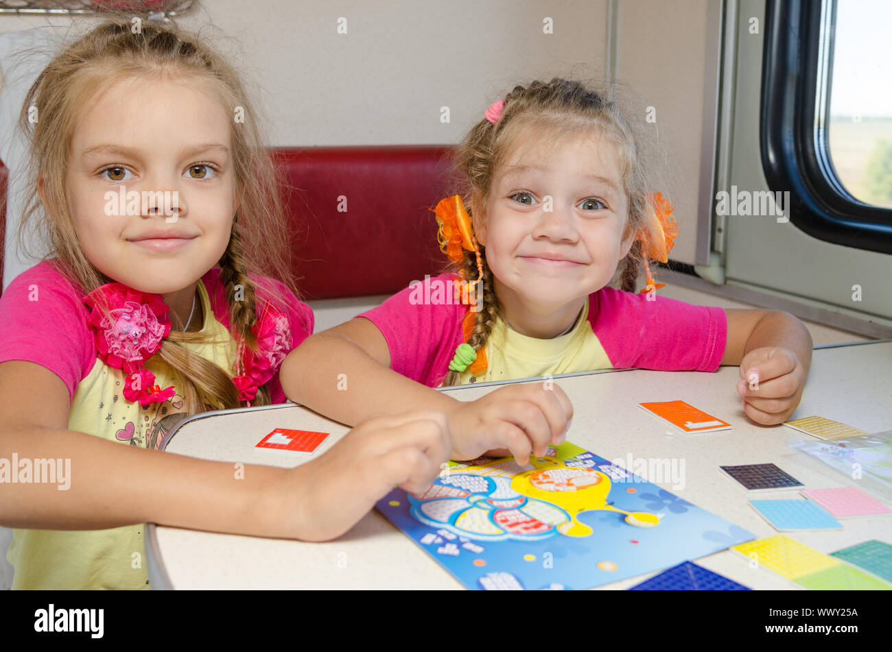 Deux petites sœurs dans le train de plaisir à jouer à la table à la place inférieure dans le compartiment de deuxième classe wagon Banque D'Images