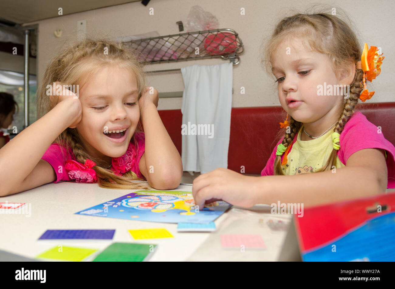 Deux jeunes filles s'amusant à jouer sur le train à la table sur la place inférieure dans le compartiment de deuxième classe wagon Banque D'Images