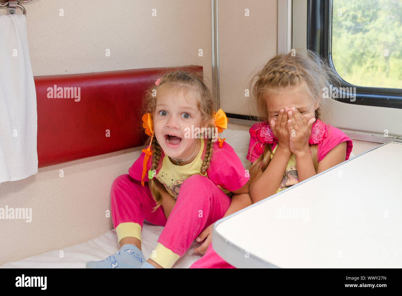 Deux petites filles gaies sont assis dans le train pour abaisser le second-class place voiture dans le même pyjama. Banque D'Images