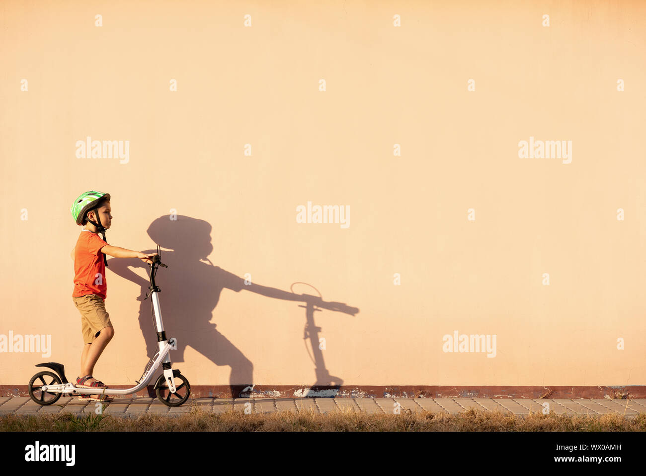 Un garçon met un casque vert sur sa tête. Banque D'Images