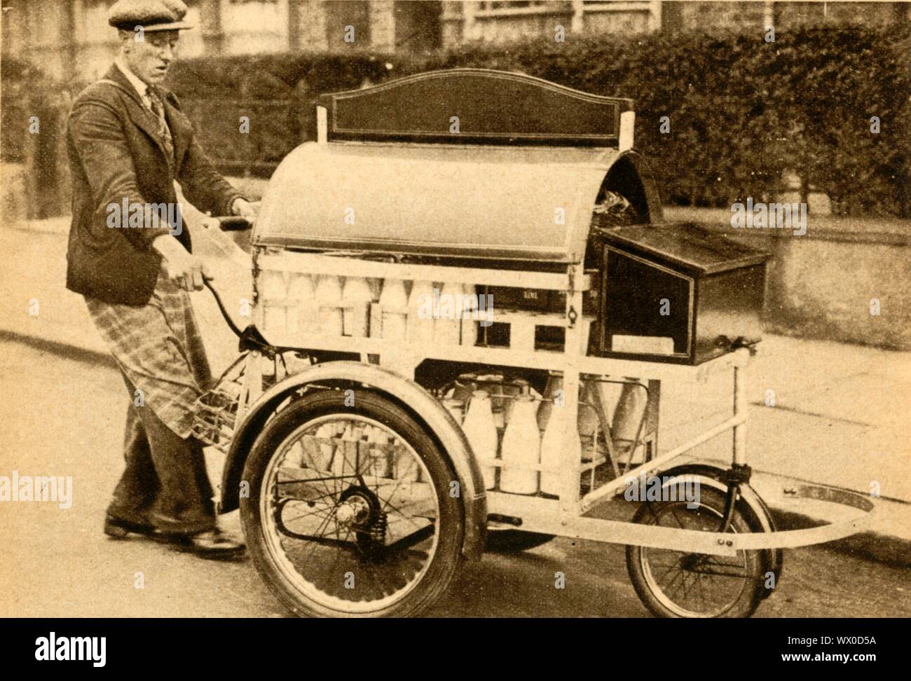 'Lait' de la PRAM, 1933. 'Pneumatiques sur roues à roulement à billes, les pare-chocs et un frein à main ont été montés sur le dernier type de lait "pram" - pour le plus grand plaisir des traverses, plus réveillé par le cliquetis de bouteilles dans les premières heures du matin ! Vingt gallons de lait peuvent être effectuées avec un minimum d'effort par l'employé, qui peut ainsi procéder à un cycle de dix-huit milles par jour. La "pram" est aussi plus hygiénique que le style ancien panier'. Le Pageant de "du siècle". Odhams Press Ltd, [1933] Banque D'Images