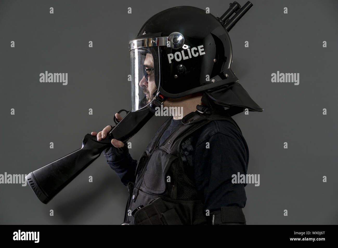 Policier de garde avec l'équipement complet pour l'anti-émeute, exécuteur des lois uniformes de protection de prêt pour les opérations de maintien de l'isolated on black Banque D'Images
