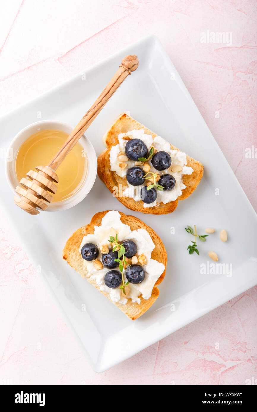 Toast avec les baies fraîches blueberry ricotta, le thym, le miel et les noisettes, servi Banque D'Images