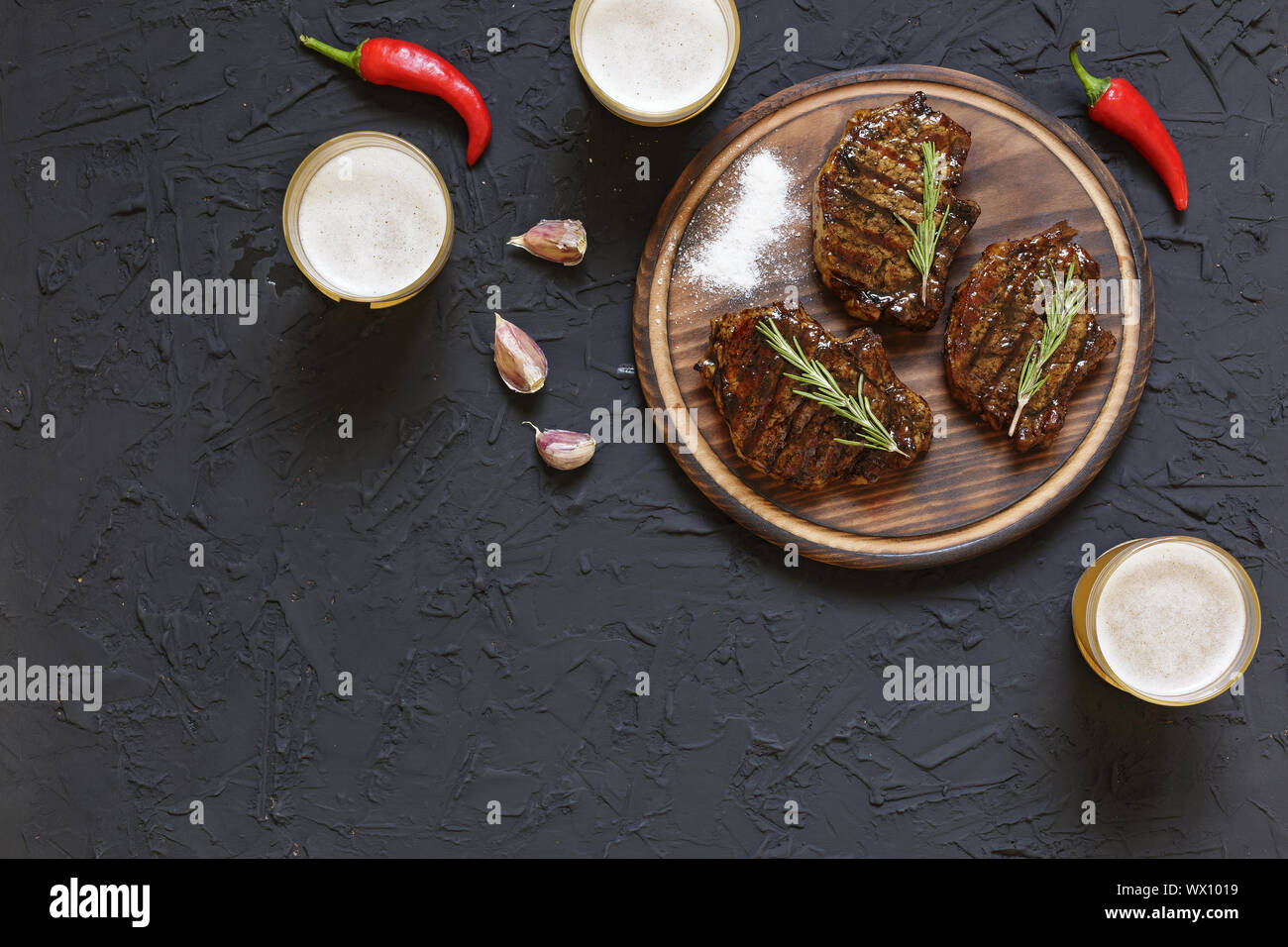 Installations pour Barbecue, des steaks, de la bière, pierre noire, tomates cerises, les poivrons, le romarin. Manger à l'extérieur. copy space Banque D'Images