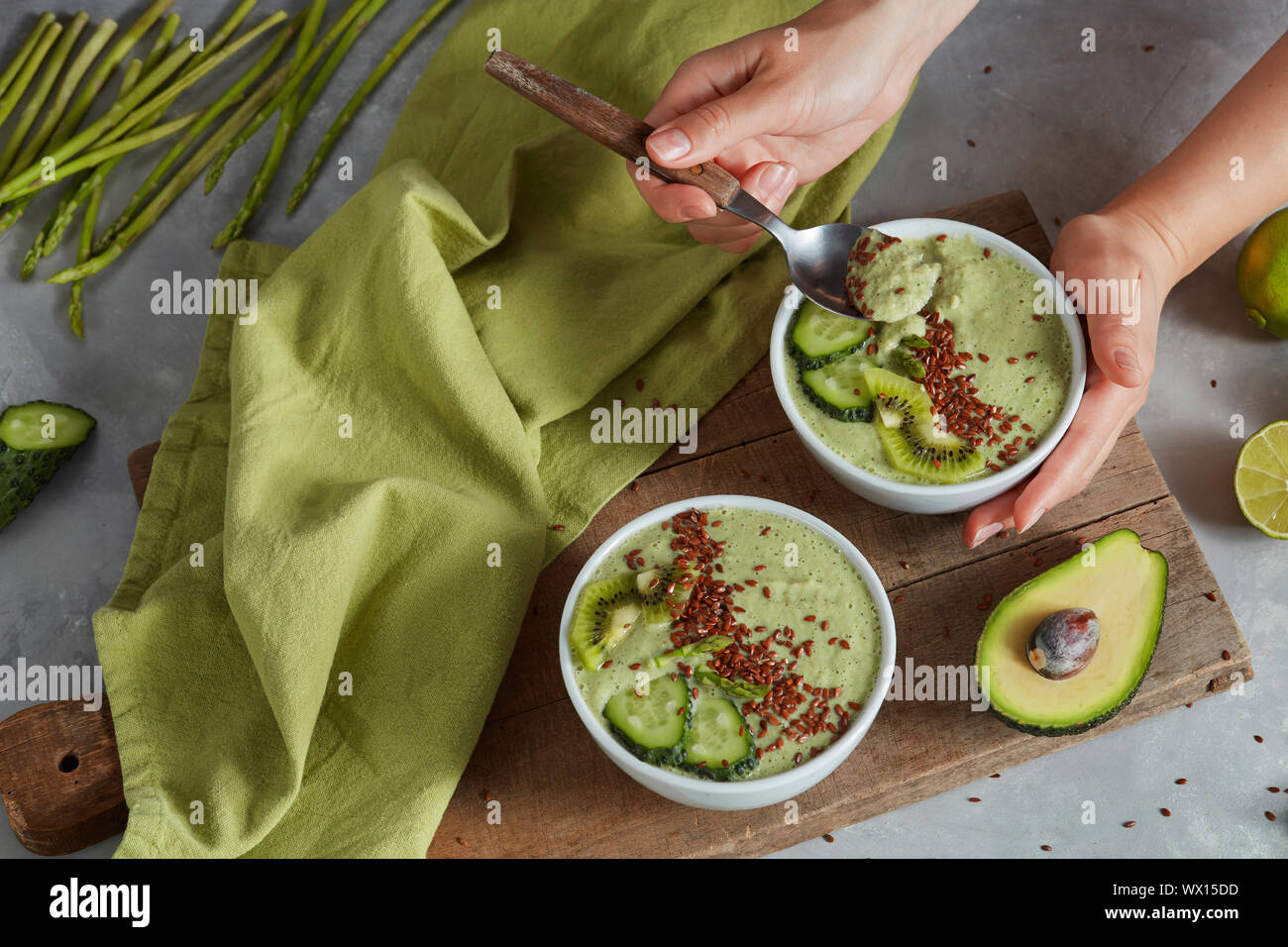 Smoothie vert bol avec l'avocat, kiwi frais et vert concombre à la main sur un fond de pierre Banque D'Images