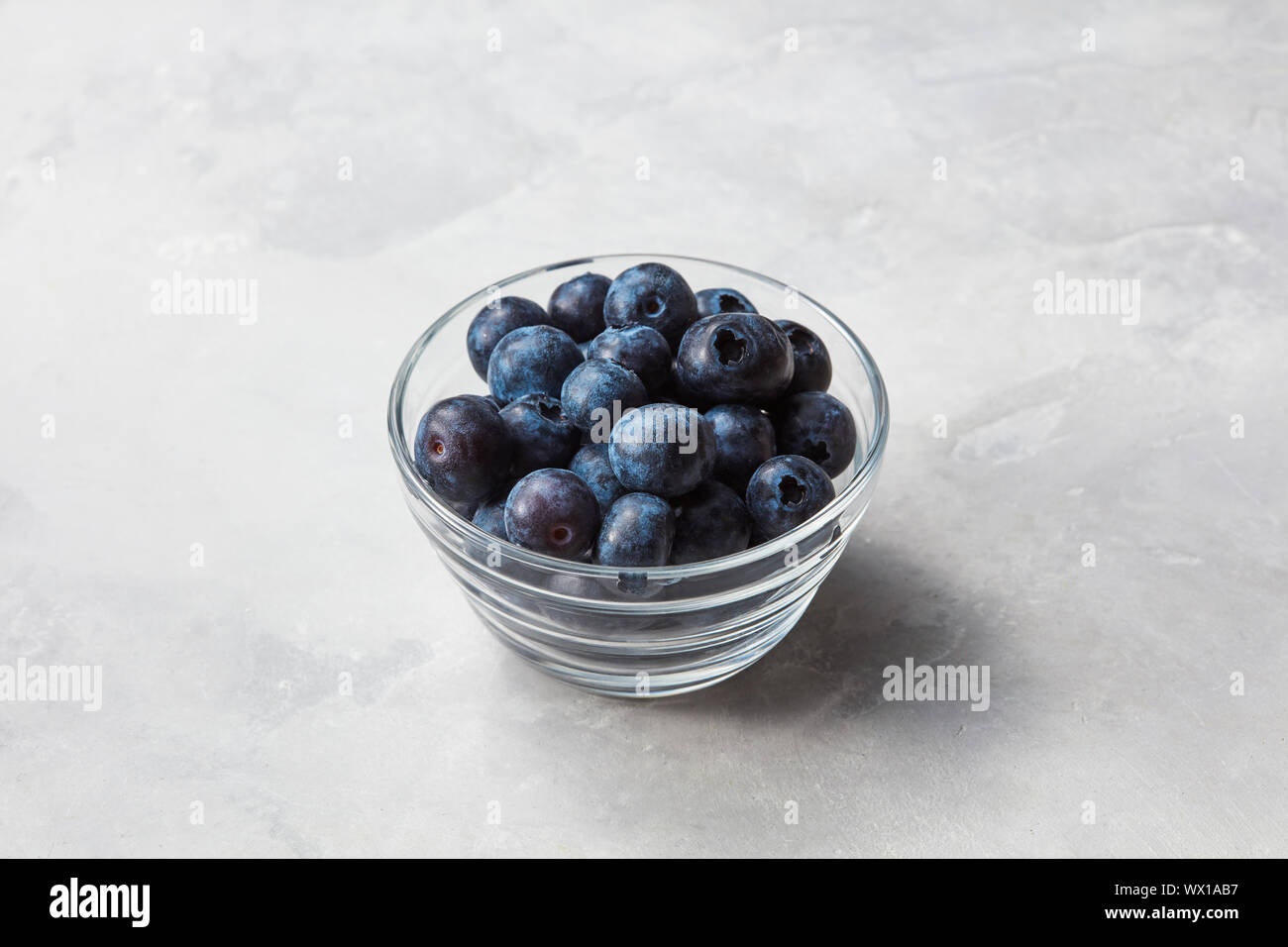 Les bleuets en est un petit bol en verre sur fond noir en gris Banque D'Images