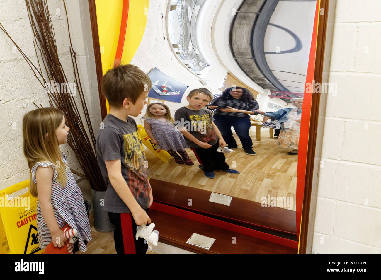 Deux enfants regardant leurs réflexions dans un drôle de miroir incurvé Banque D'Images