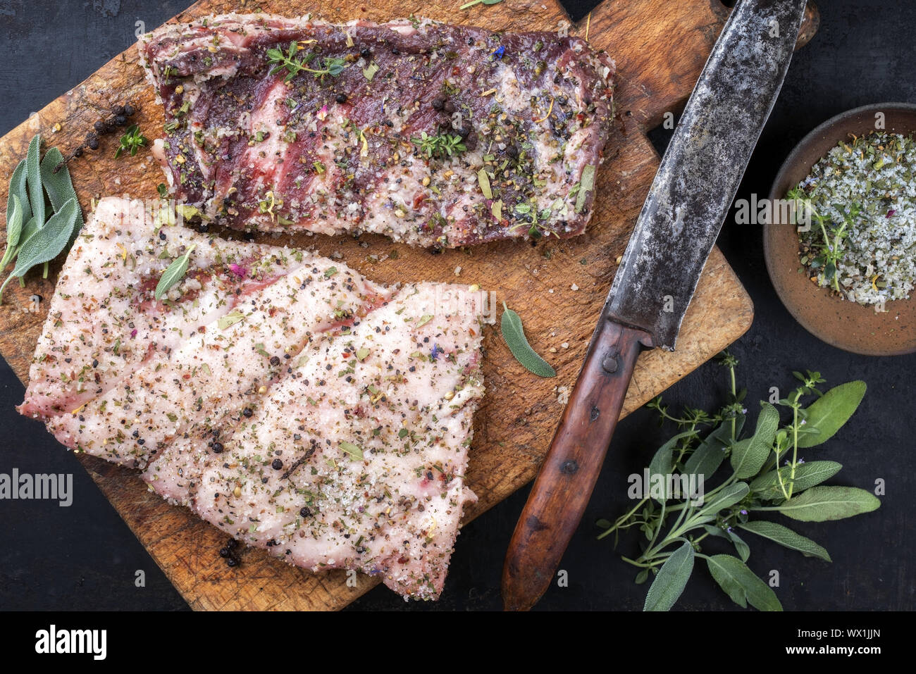 Flanc de porc sauvage jaune avec des épices comme vue de dessus sur une vieille planche à découper Banque D'Images