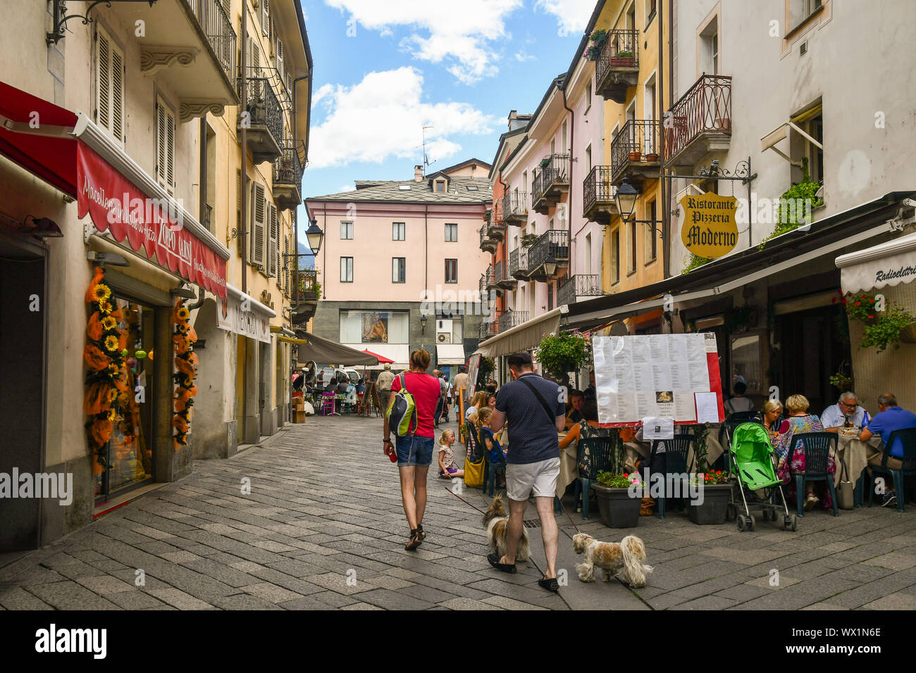 Ruelle étroite dans le centre de la ville alpine d'aoste avec les gens et les touristes en train de déjeuner dans les restaurants de plein air en été, de la vallée d'aoste, Italie Banque D'Images