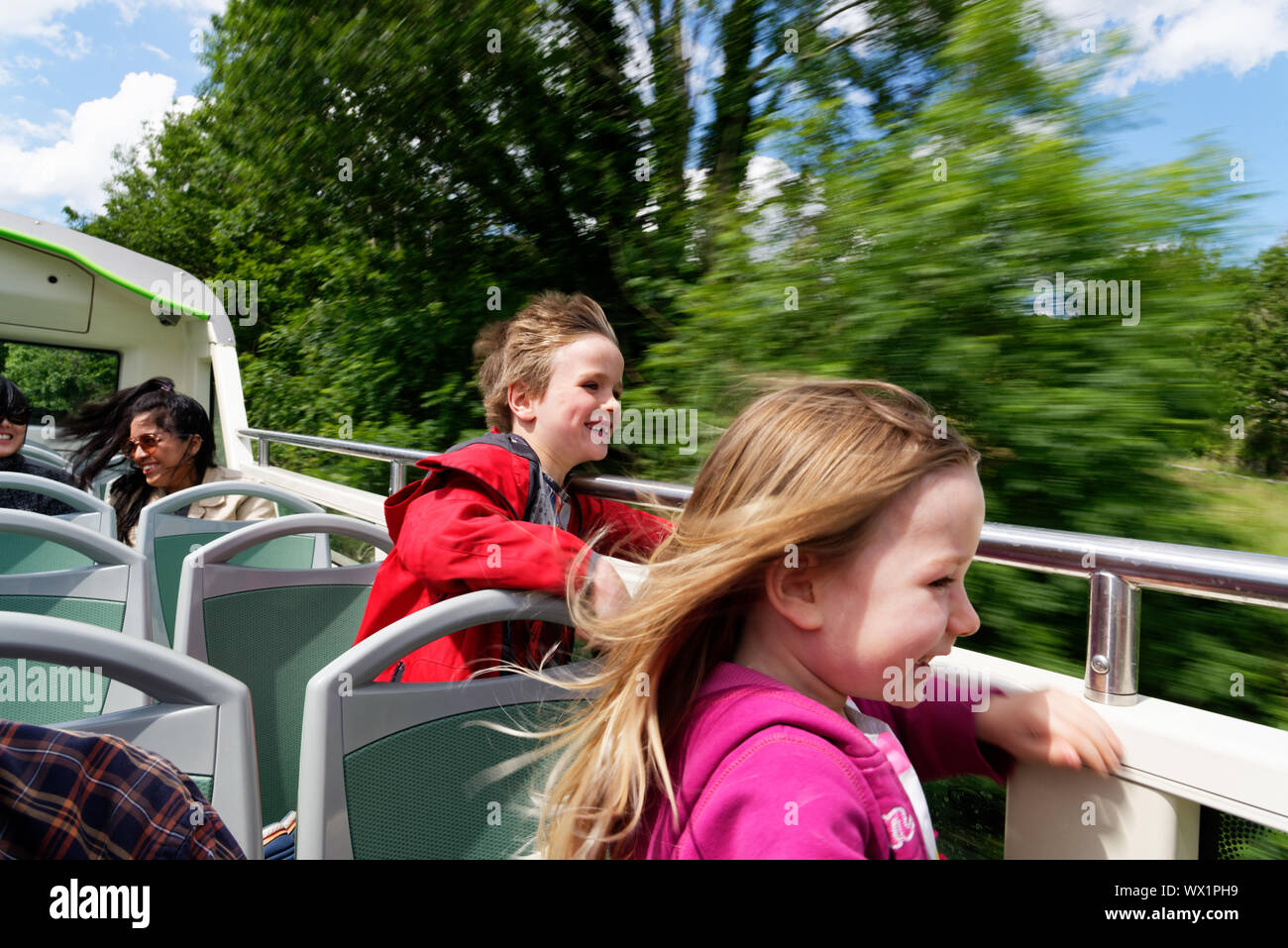 Deux enfants rire avec vent dans leurs visages sur un bus à impériale à toit ouvert dans le lac ème arrondissement, Cumbria, Royaume-Uni Banque D'Images