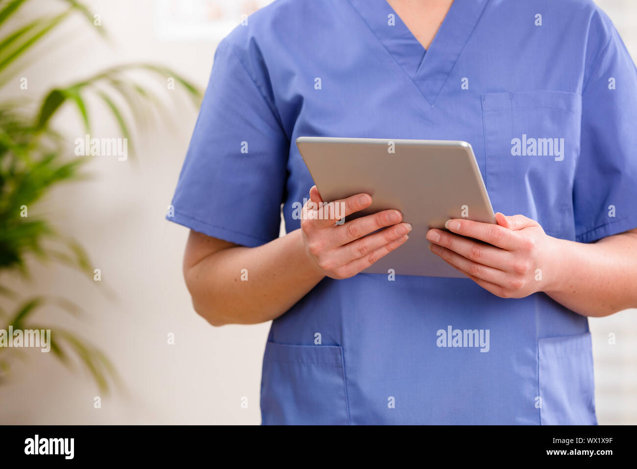 Femelle adulte médecin ou infirmière à la recherche à l'image numérique ou d'un rapport sur une tablette Banque D'Images