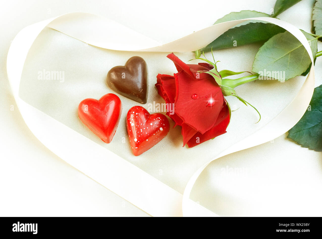 Carte de la Saint-Valentin. Coeurs en chocolat et rose rouge Banque D'Images