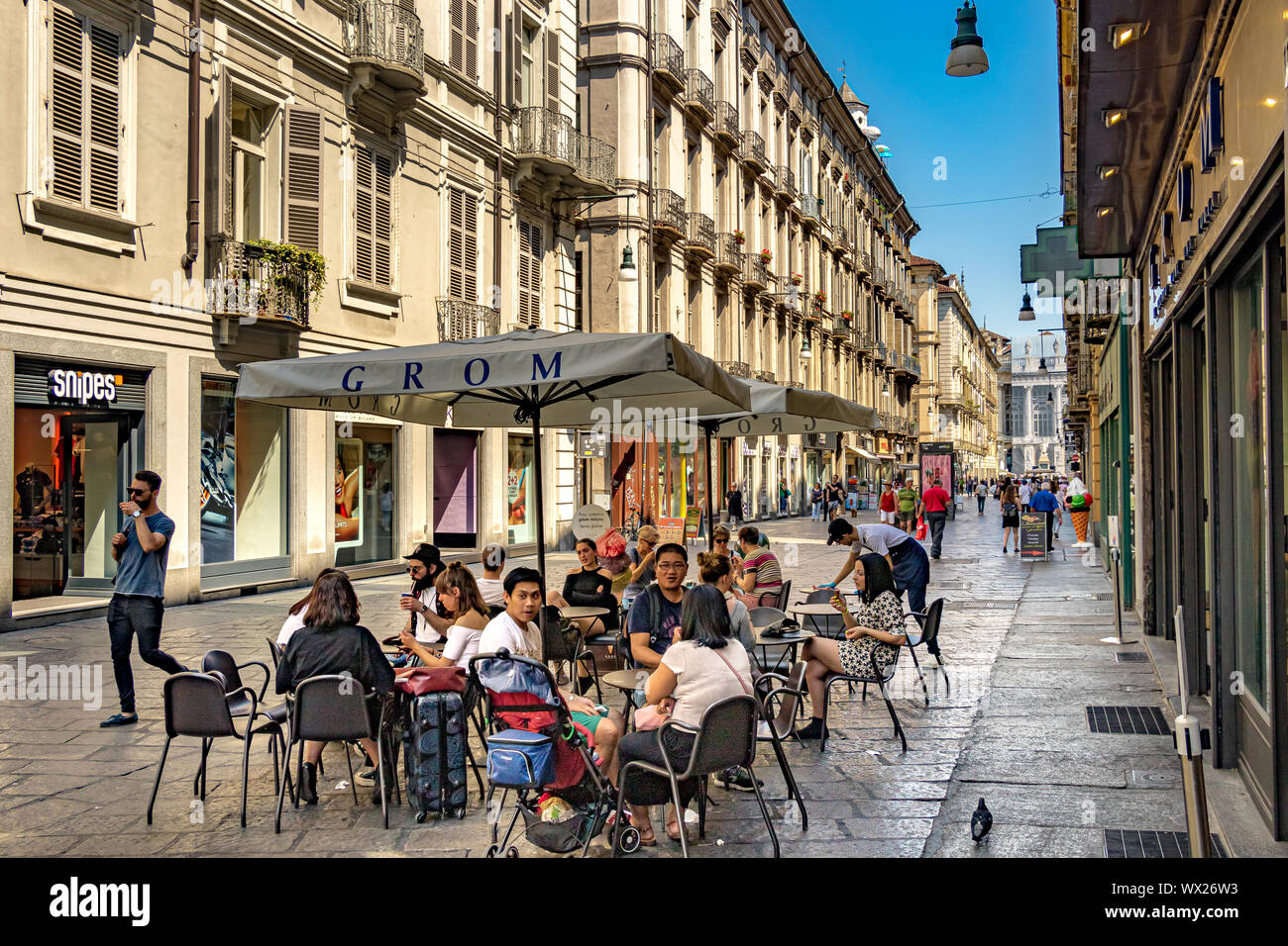 Les gens assis à l'extérieur de Grom gelateria mangeant du geleato sur la via Garibaldi à Turin, Italie Banque D'Images