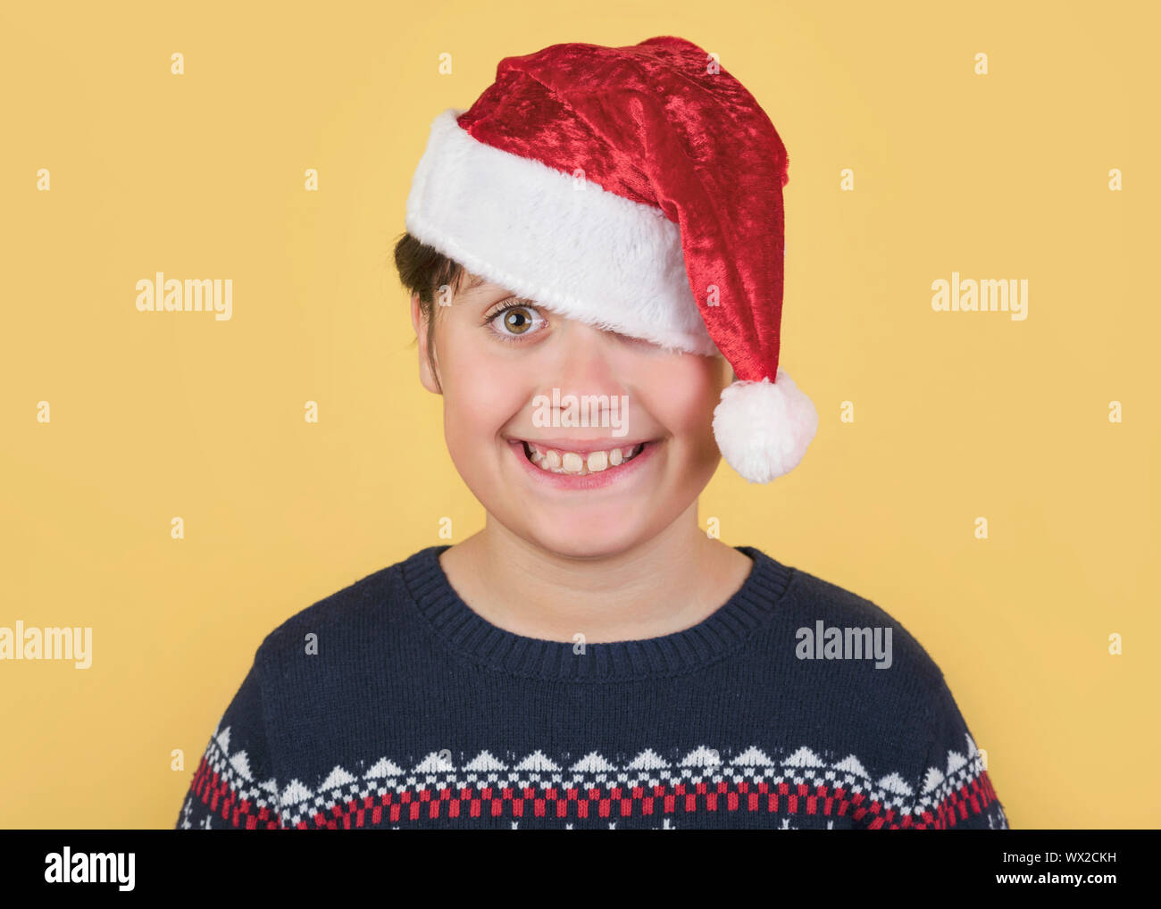 Child Wearing Christmas Santa Claus Hat sur fond jaune Banque D'Images