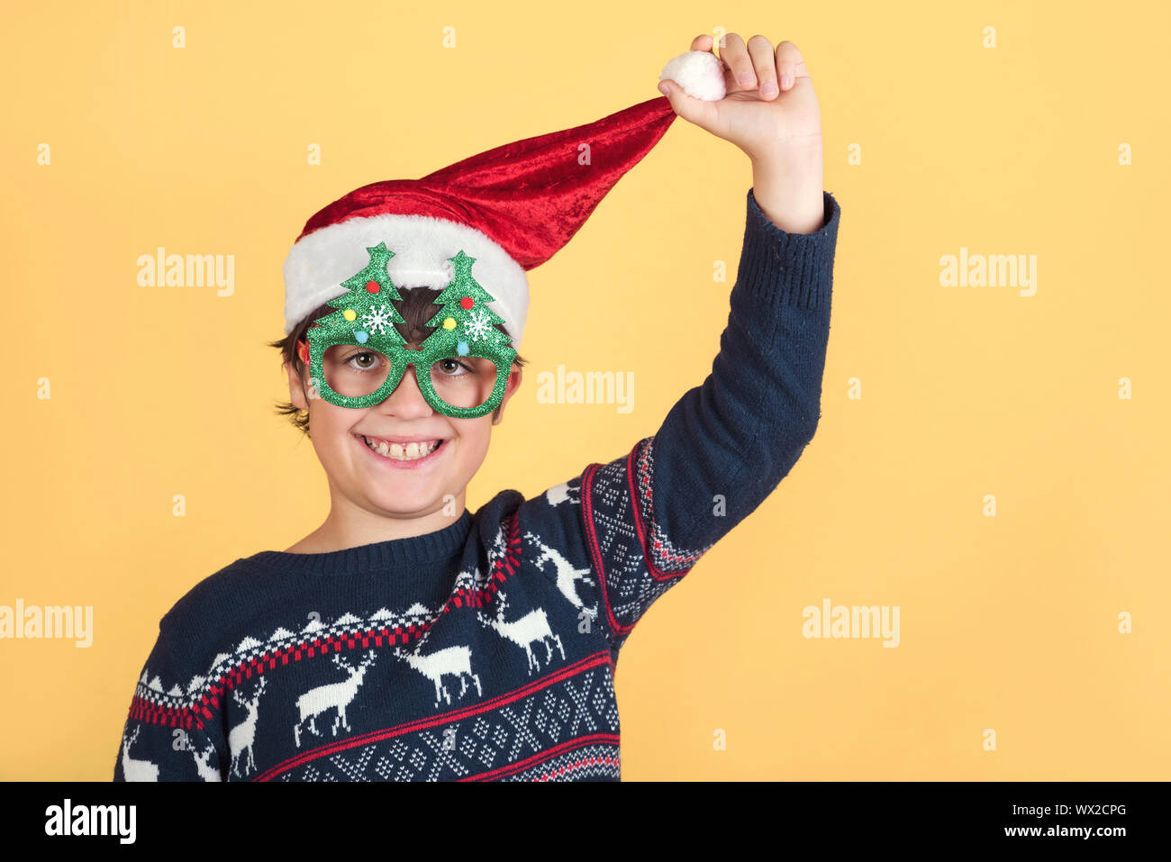 Child Wearing Christmas Santa Claus Hat et drôles de lunettes sur fond jaune Banque D'Images