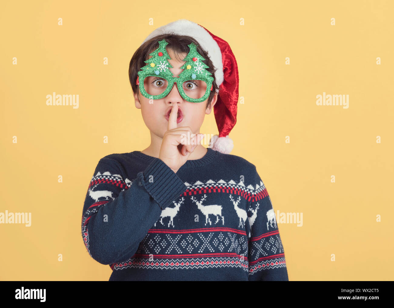 Child Wearing Christmas Santa Claus Hat demande silence sur fond jaune Banque D'Images