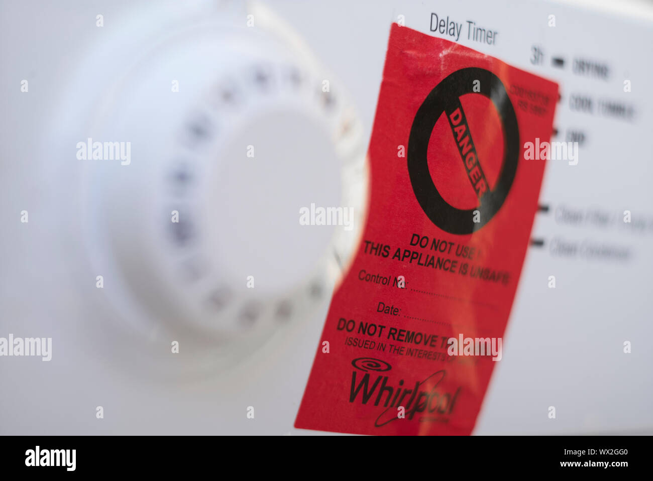 Signe de danger rouge collé sur la face avant d'un sèche-linge Whirlpool Hotpoint blanc Banque D'Images