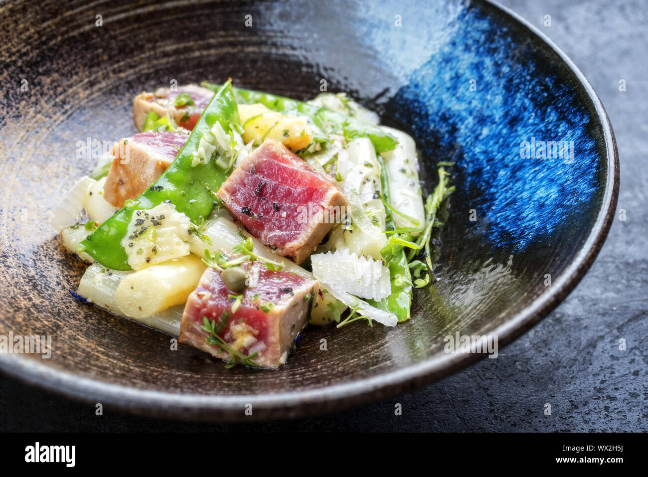 Tataki de thon poêlé moderne salade de filet avec du sucre d'asperges blanches s'enclenche et parmesan en vue de dessus sur une plaque Banque D'Images