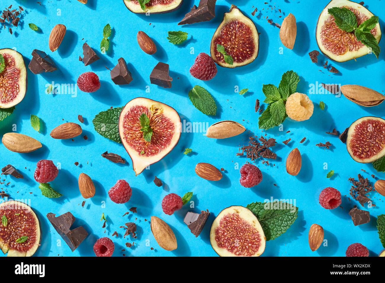 Modèle d'été avec du chocolat, fruits rouges, amandes, figues, menthe sur un fond bleu. À partir de la composition des aliments sucrés créatif dans naturel Banque D'Images Modèle d'été avec du chocolat, fruits rouges, amandes, figues, menthe sur un fond bleu. À partir de la composition des aliments sucrés créatif dans naturel Banque D'Images