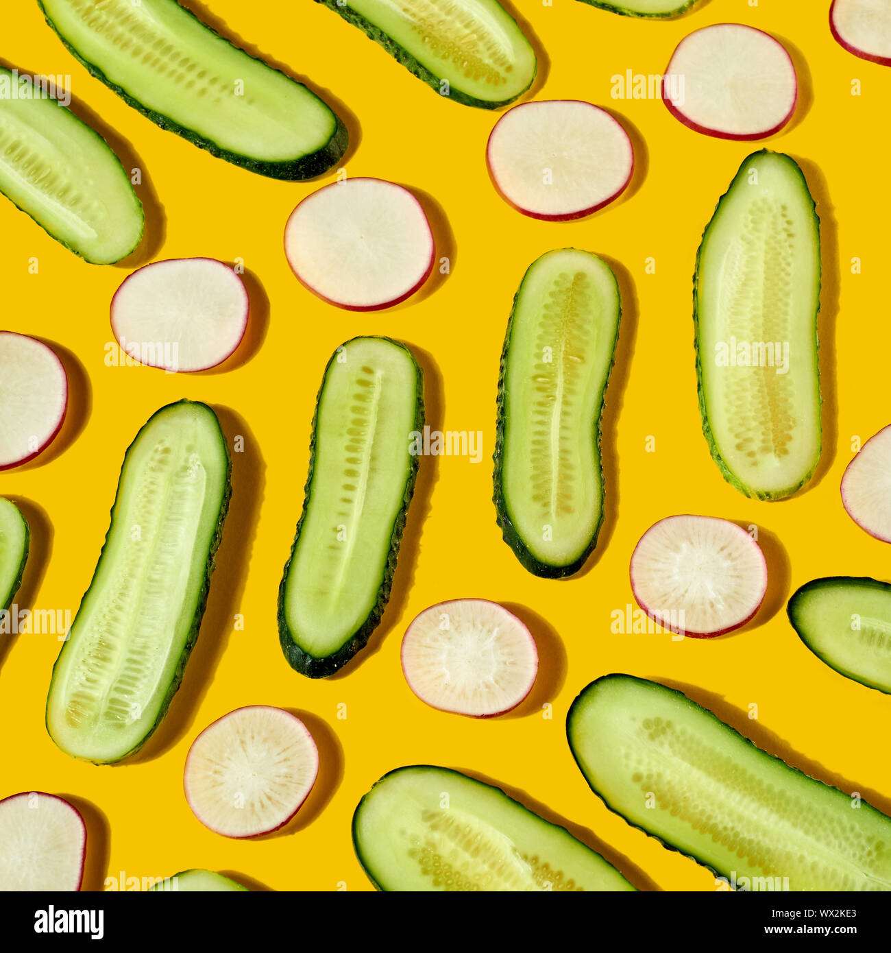 Vegan aliments diététiques - cocumber les légumes fraîchement cueillis et radis comme un motif géométrique sur fond jaune. Mise à plat. Banque D'Images Vegan aliments diététiques - cocumber les légumes fraîchement cueillis et radis comme un motif géométrique sur fond jaune. Mise à plat. Banque D'Images