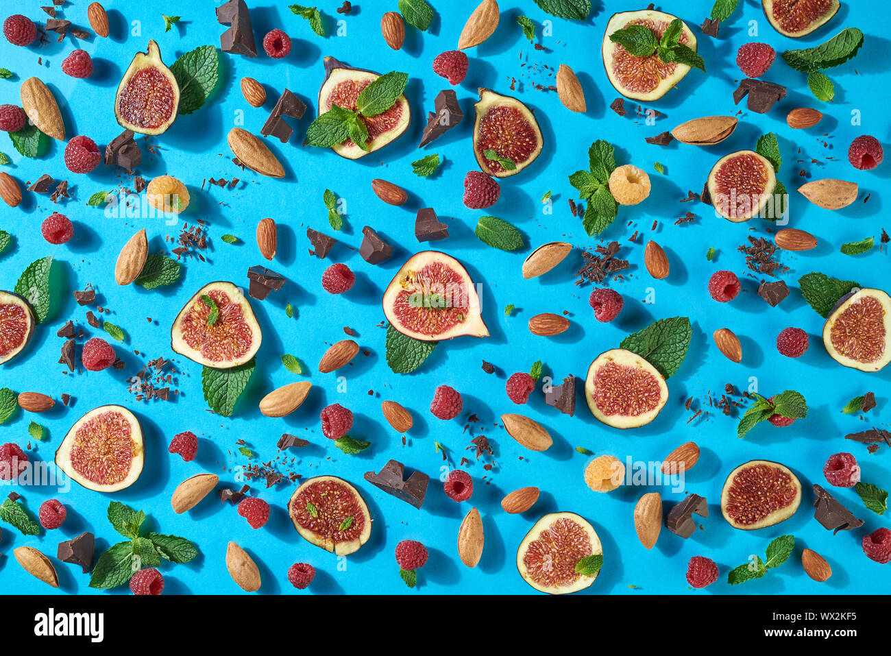 Motif de dessert sucré ripr figues, noix, chocolat, feuille de framboise fraîche, voulait dire sur un fond bleu. Mise à plat Banque D'Images Motif de dessert sucré ripr figues, noix, chocolat, feuille de framboise fraîche, voulait dire sur un fond bleu. Mise à plat Banque D'Images