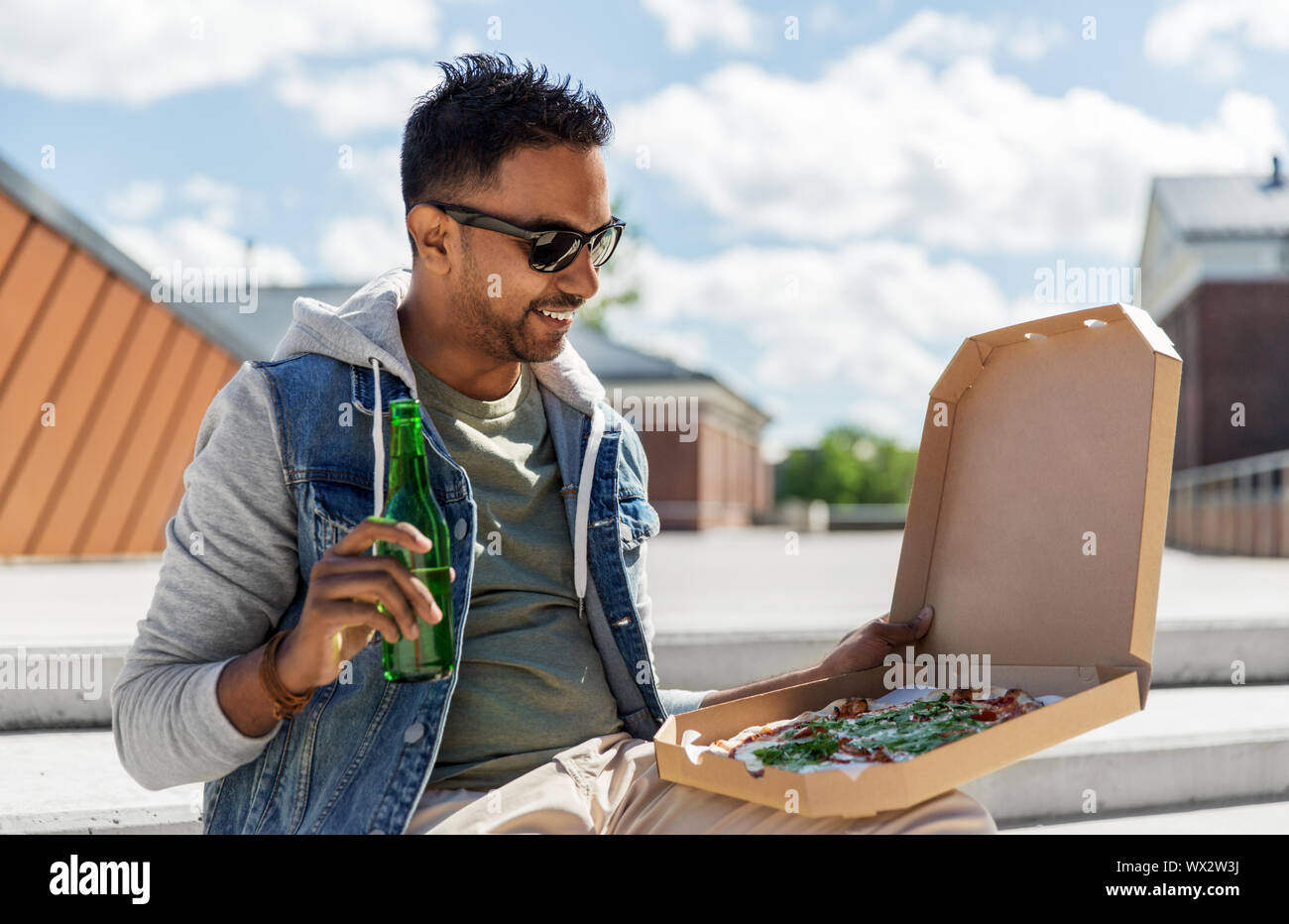 L'homme indien avec pizza et boire de la bière en plein air Banque D'Images