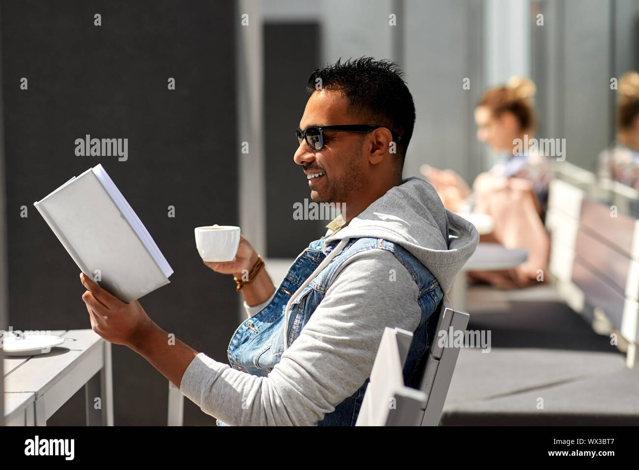 Man reading book et de boire du café au café de la ville Banque D'Images