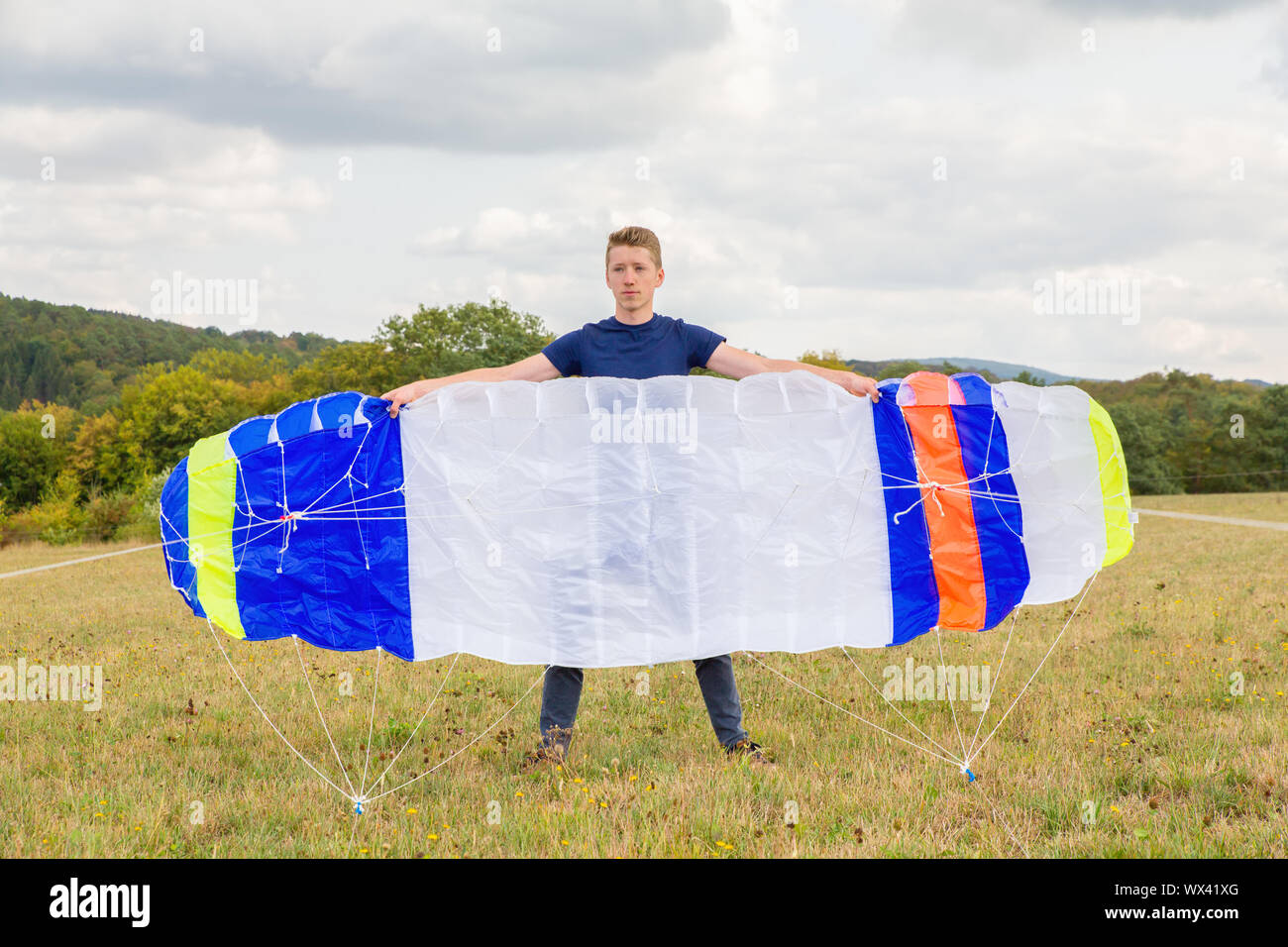 Young man holding néerlandais kite matelas en paysage Banque D'Images