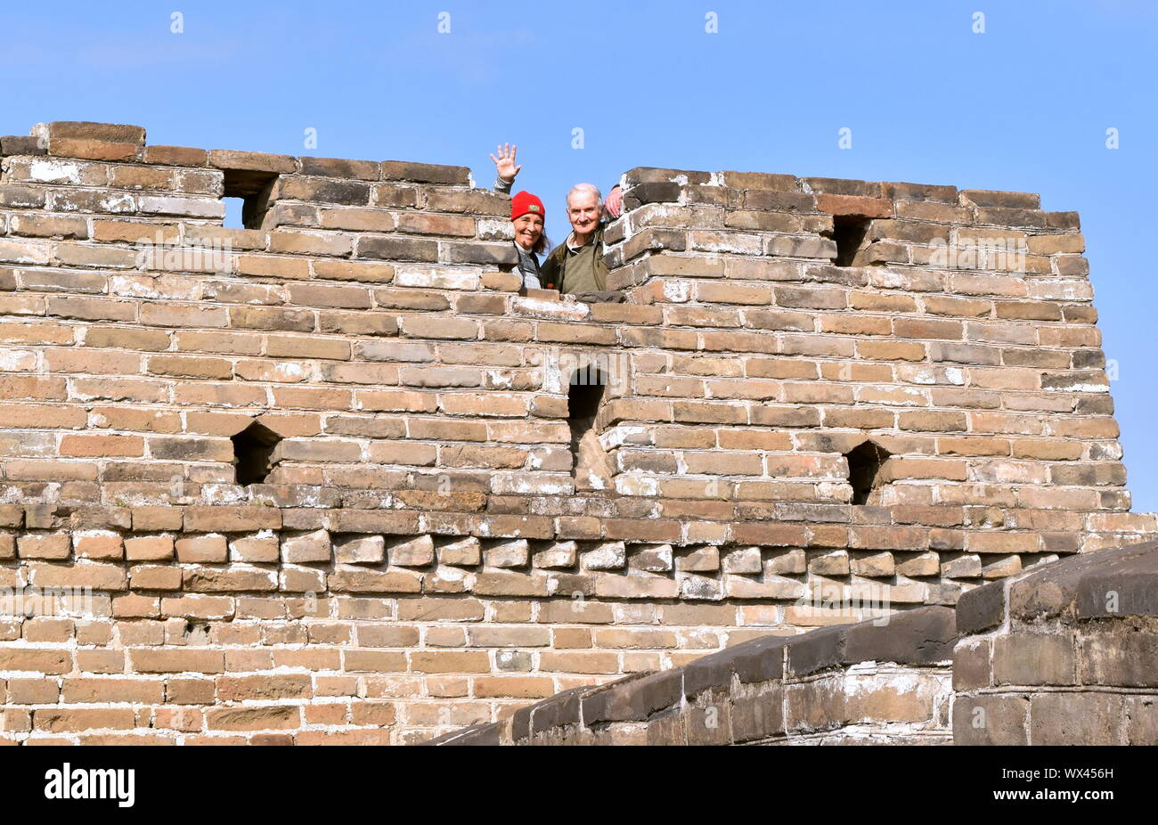 Senior tourist couple vagues de Grande Muraille de Chine, la tour de garde, la Chine Mutianyu Banque D'Images