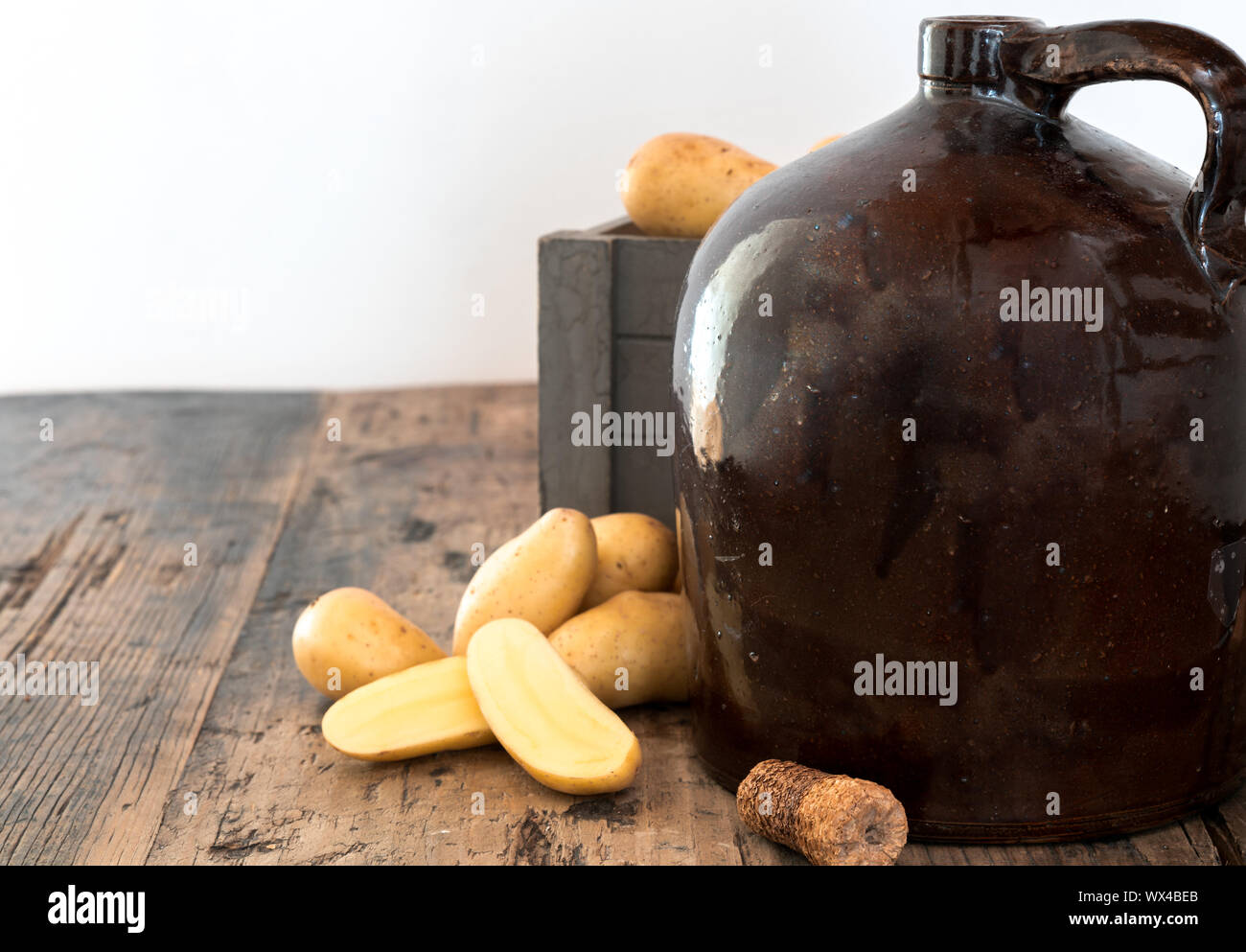 Moonshine vintage sur une table en bois rustique avec des pommes de terre et d'épis de maïs cork Banque D'Images