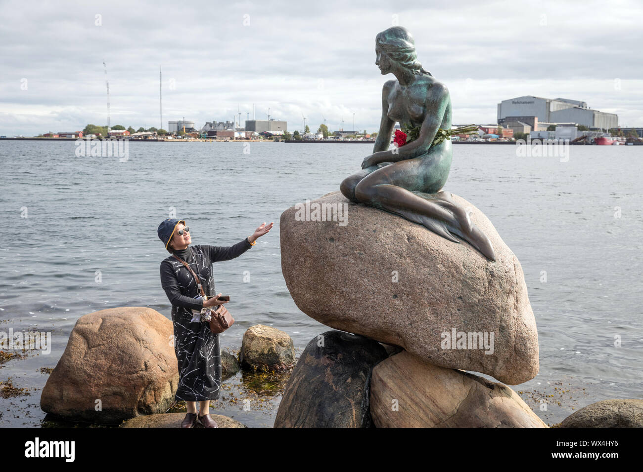 Un visiteur avec Edvard Eriksen's statue de la Petite Sirène à Langelinie, Copenhague, Danemark Banque D'Images