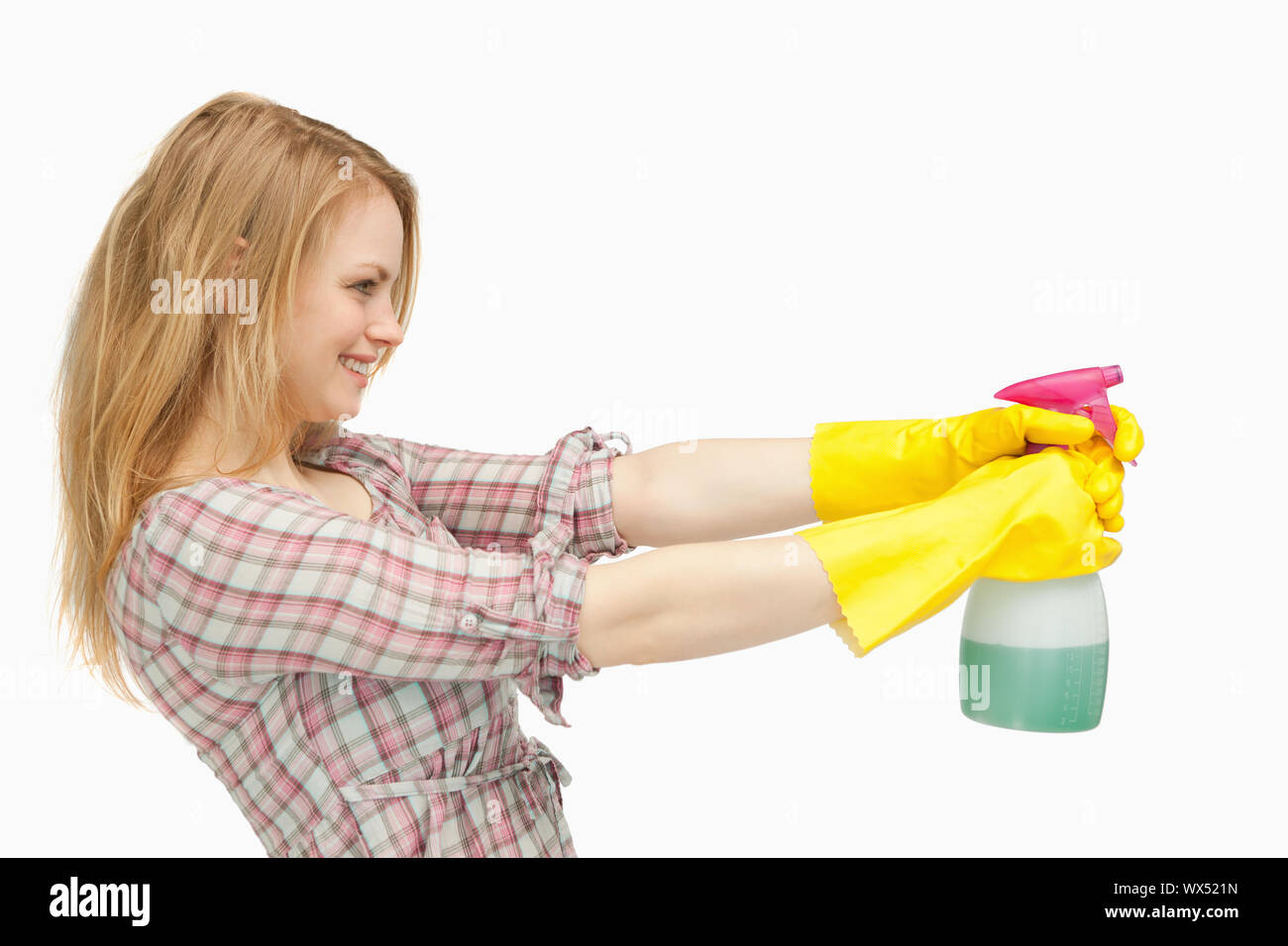 Fair-haired woman tenant une bouteille de jet tout en souriant contre fond blanc Banque D'Images