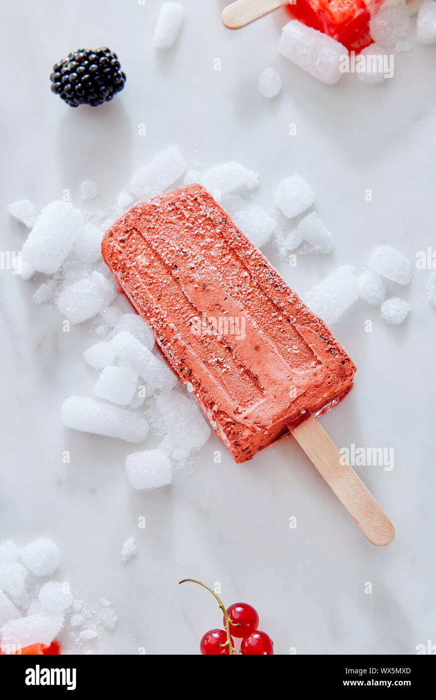 Berry la crème glacée, sorbet cassis sucettes glacées en couleur de l'année 2019 de coraux vivants sur de la glace concassée Pantone sur un marbre backg Banque D'Images