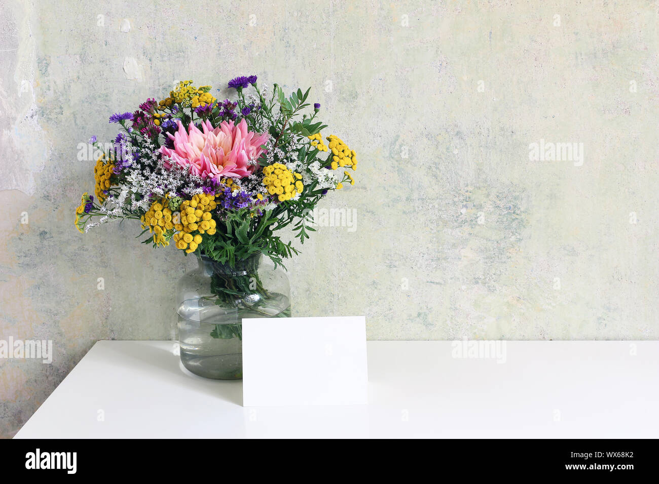 Vase en verre coloré avec de beaux bouquet de lisianthus, tansies et aster fleurs. Grunge vieux mur arrière-plan. Mariage, anniversaire féminin maquette des lieux Banque D'Images