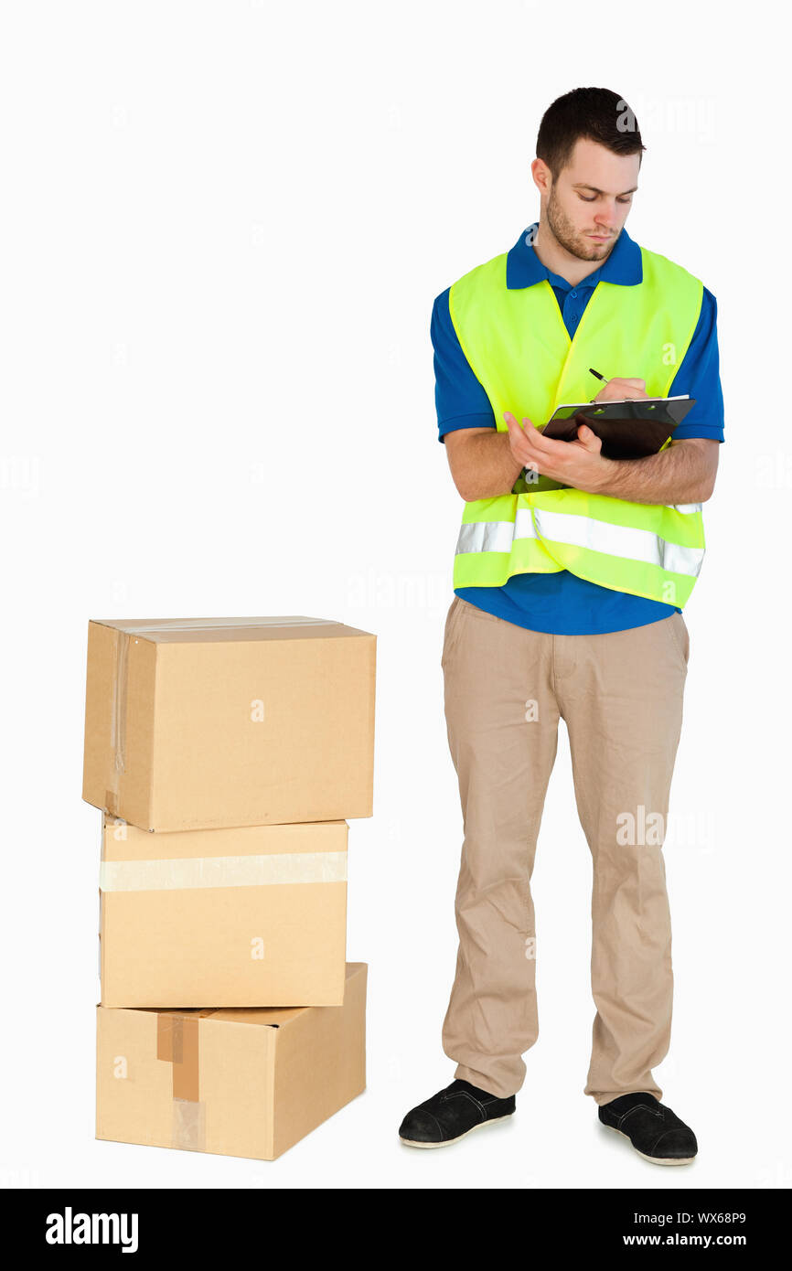 Young delivery man filling in delivery note sur un fond blanc. Banque D'Images