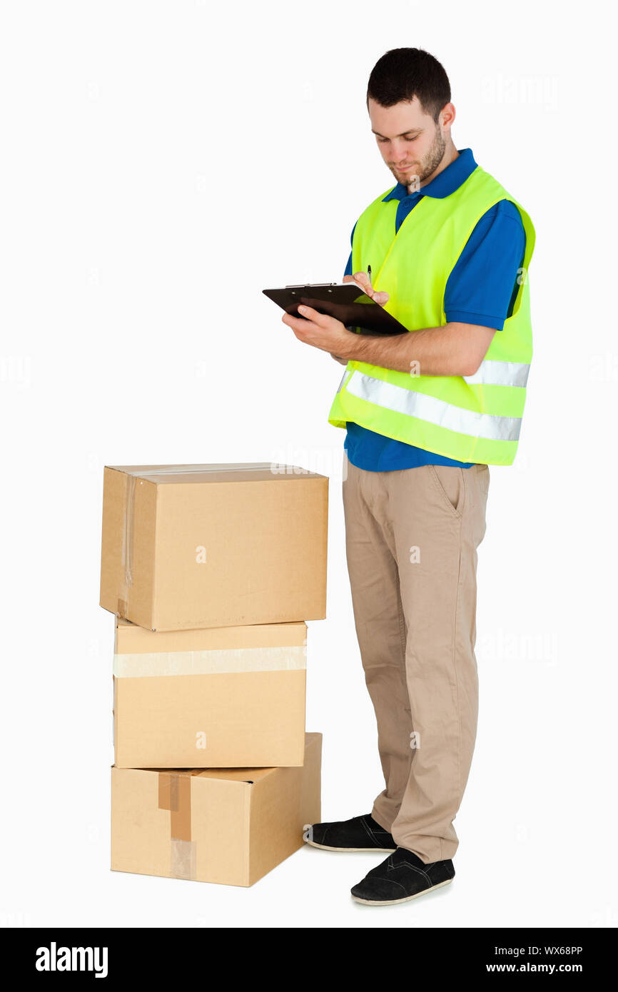 Vue latérale du young delivery man filling in delivery note sur un fond blanc. Banque D'Images