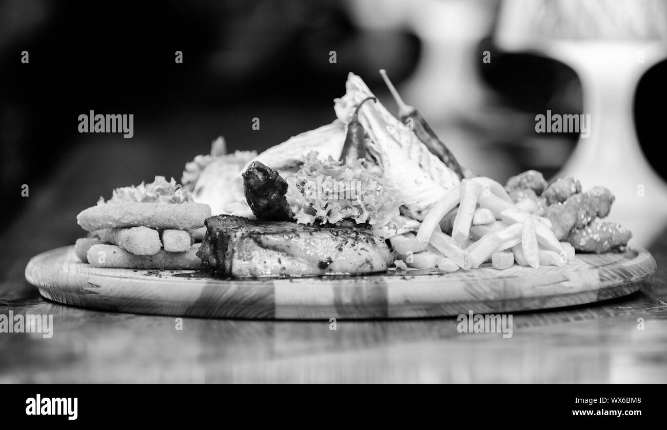 Les repas au restaurant. Planche de bois avec beaucoup de frites et bâtonnets de poisson viande burrito steak servi avec une salade. Menu snack-bar. Calories élevé pour le groupe d'amis. De délicieux en-cas savoureux. Snack pour la bière. Banque D'Images