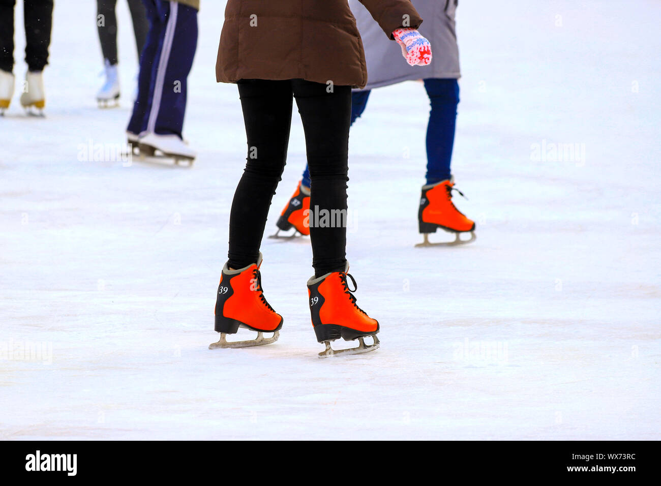 Patinoire d'hiver. La jeune fille dans l'équitation patins rouge sur la glace. Famille active sport pendant le Children s vacances d'hiver et la saison froide. Le sport scolaire Banque D'Images