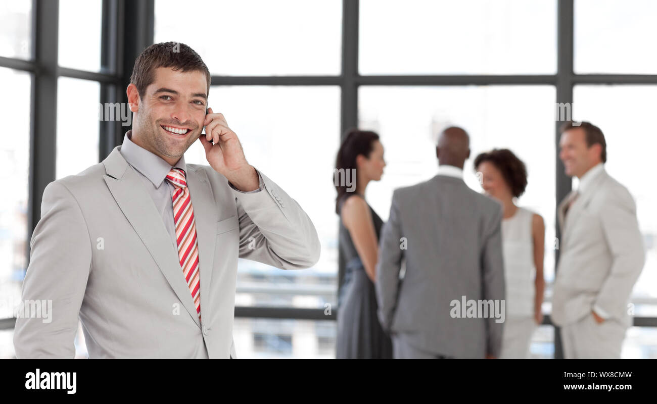 Beau businessman on phone in office avec son équipe Banque D'Images