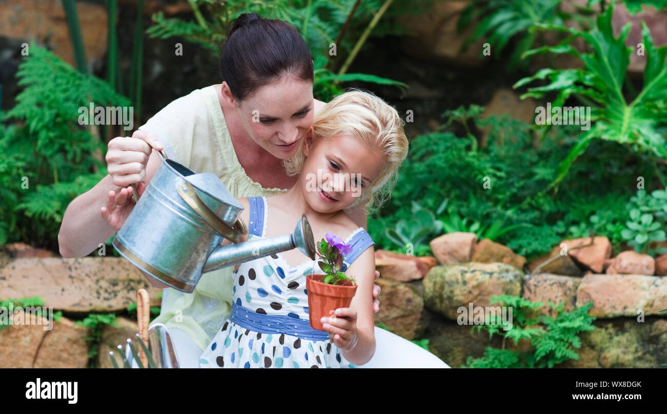 Mère et fille rayonnante de planter dans leur jardin Banque D'Images