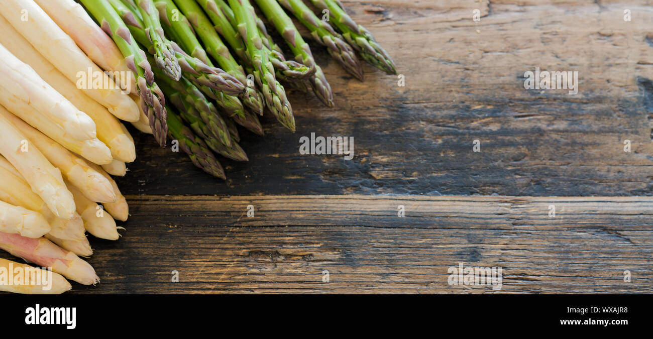 Produits frais bio asperges vertes et blanches sur une vieille table en bois brun rustique Banque D'Images