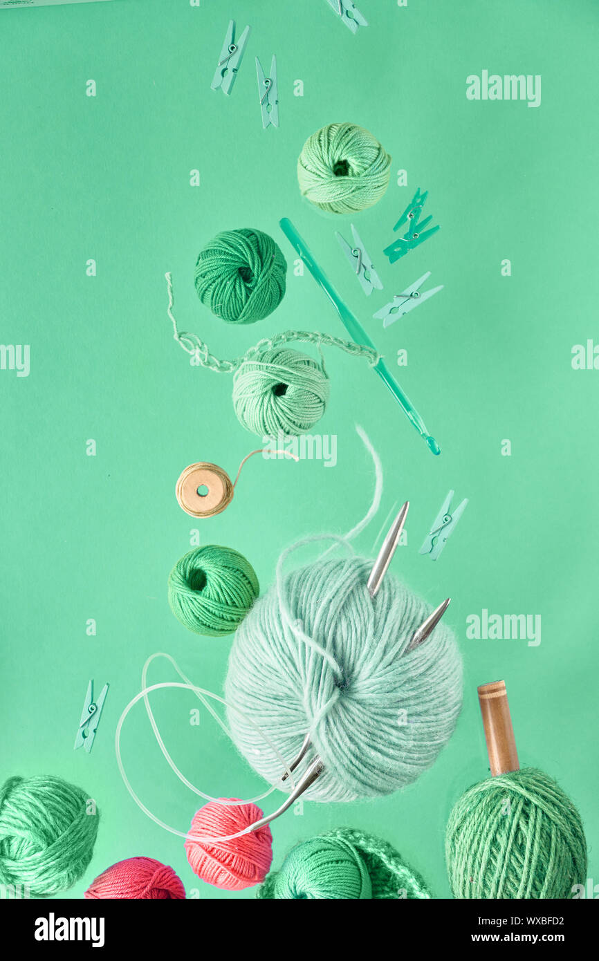Divers fil de laine et des aiguilles à tricoter, passe-temps de tricot créatif sur fond couleur menthe neo papier fond Banque D'Images