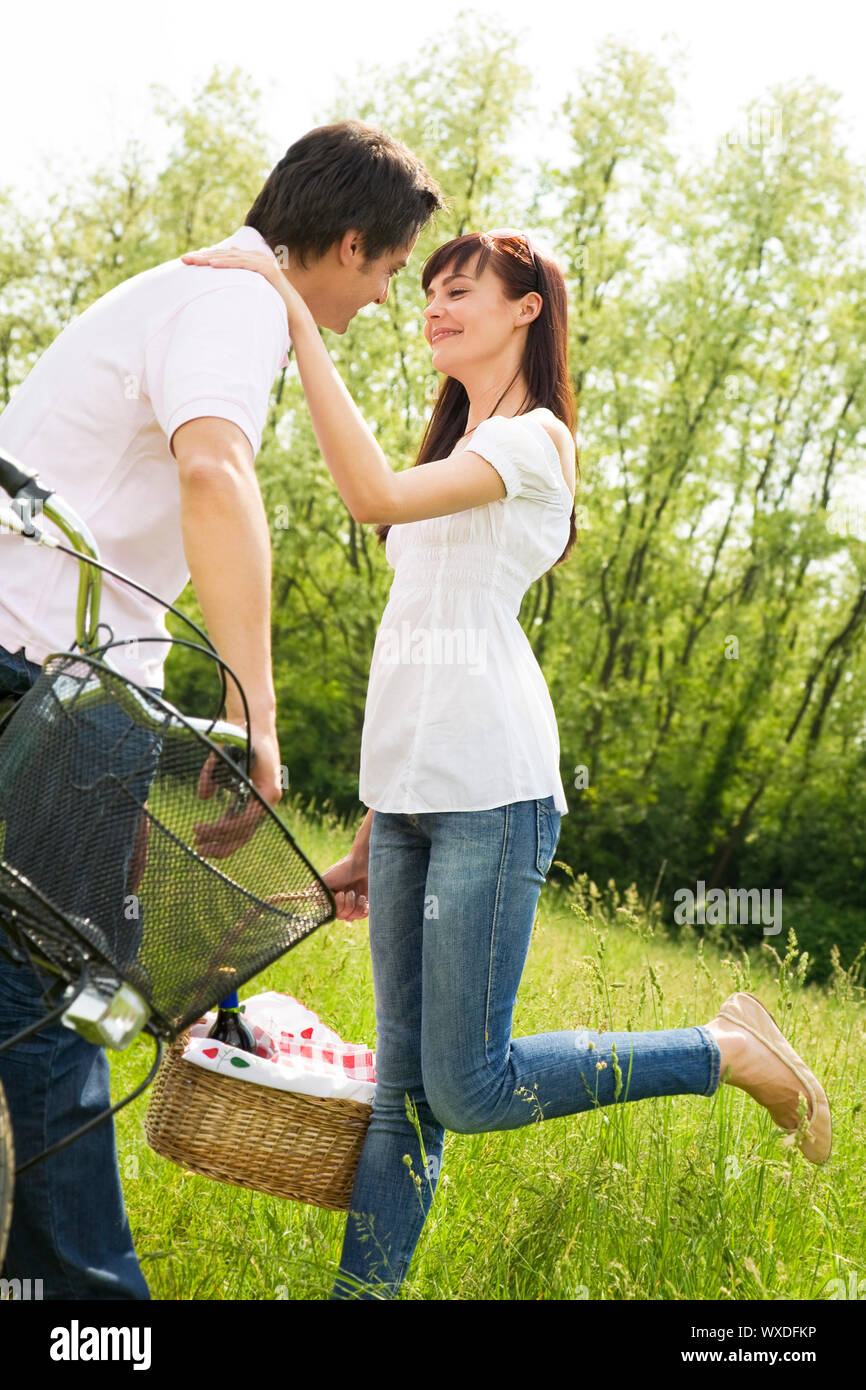 Couple in park with holding panier à pique-nique, des baisers. Femme soulève sa jambe Banque D'Images