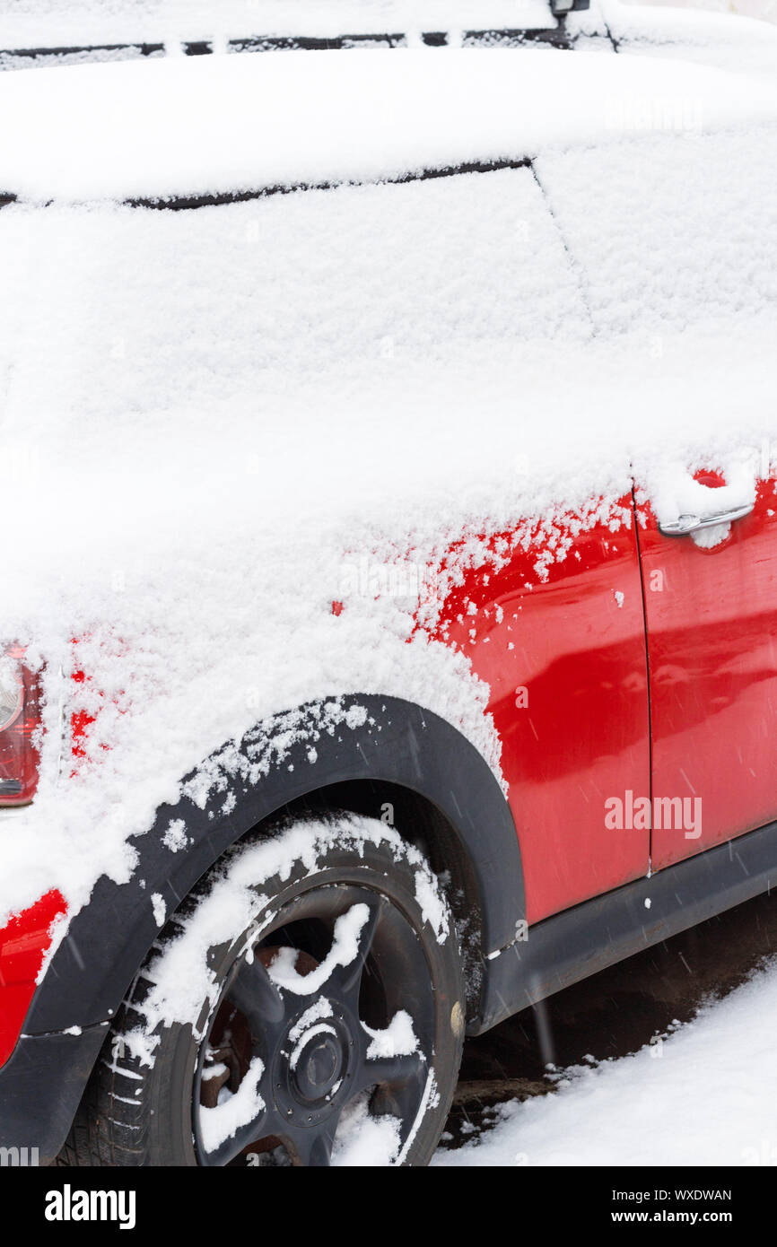 Voiture rouge couverte de neige sur le stationnement en hiver Banque D'Images